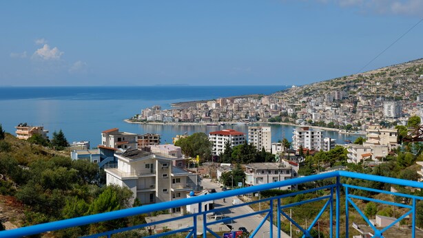 A coastal cityscape with a view of the sea and a hill with buildings. - Stunning 1-bed House in Sarandë (Sarandë)