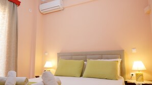 Een hotelkamer met een bed, groene kussens, twee bedlampjes en opgerolde handdoeken op het bed.