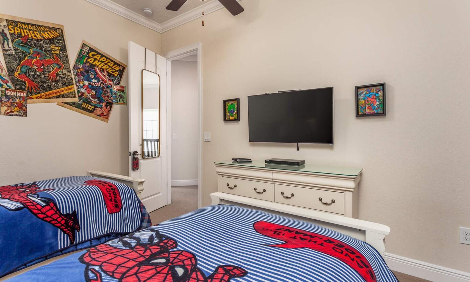 Une chambre avec deux lits, une télévision et des affiches de bandes dessinées accrochées au mur.