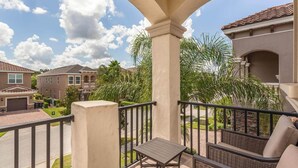 A balcony with a view of neighboring houses, a small table, and wicker furniture. - Luxury Private Villa with Large Pool on Reunion Resort and Spa, Orlando Villa 4588 (Orlando)