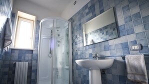 A bathroom with a glass-enclosed shower, a sink, and a mirror.