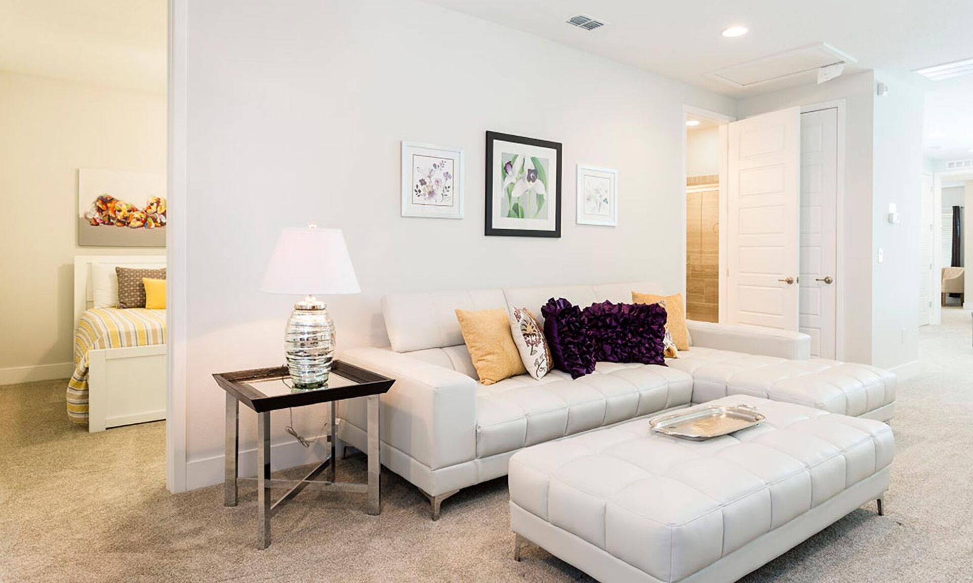 A modern living room with a white sofa, a side table with a lamp, and a large window.