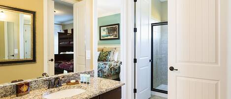 A bathroom with a sink, mirror, and a shower area.