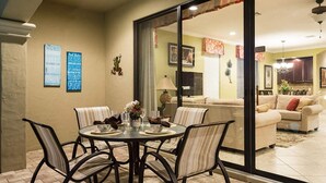 A dining area with a round table, chairs, and a glass partition. There are two signs on the wall, one labeled "Patio Rules" and the other "Pool Rules". - Beautiful 5 Star Villa on Reunion Resort and Spa with Large Private Pool, Orlando Villa 4597 (Orlando)