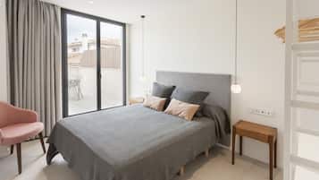 A bedroom with a large bed, a chair, a bedside table, and a view of the outside.
