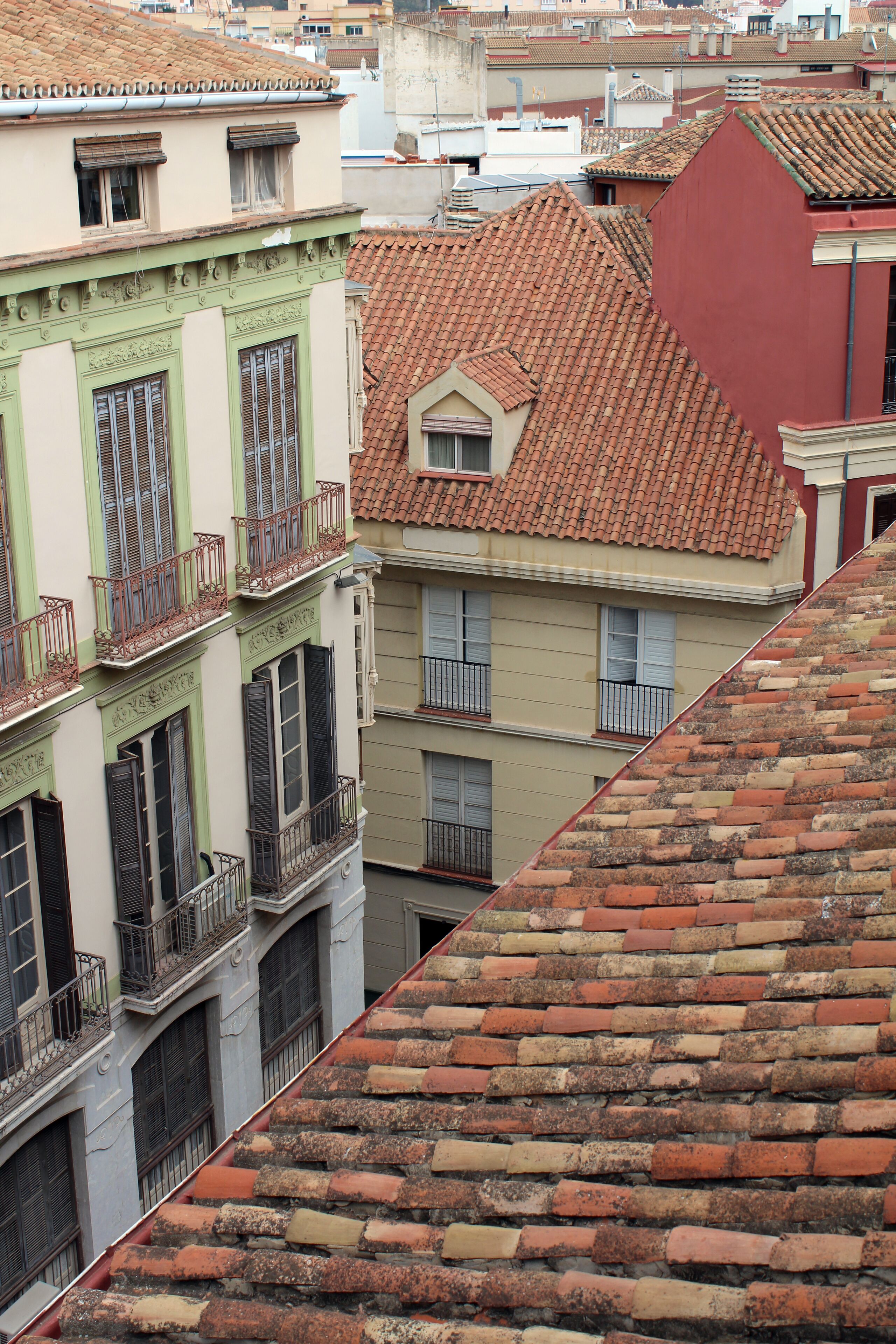 Une vue sur un paysage urbain avec des bâtiments dotés de toits recouverts de tuiles rouges et de balcons.