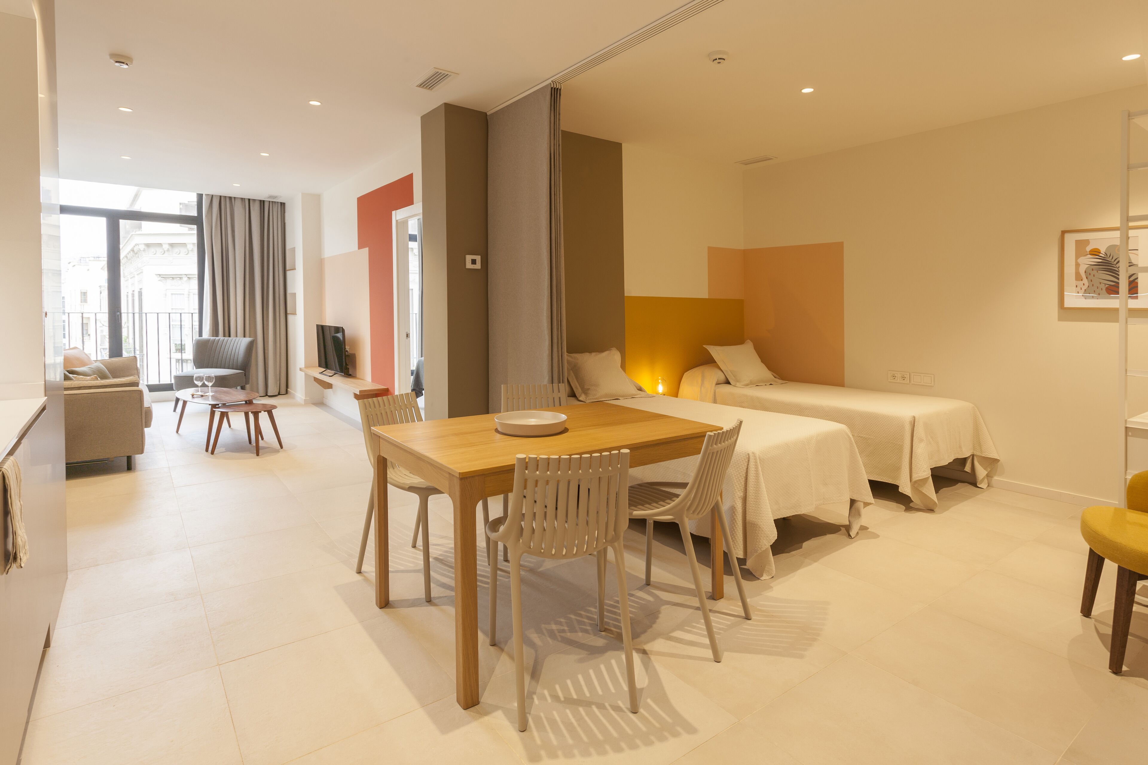 Une chambre d’hôtel moderne dotée d’un coin repas, de deux lits, d’une télévision et d’un balcon avec vue.