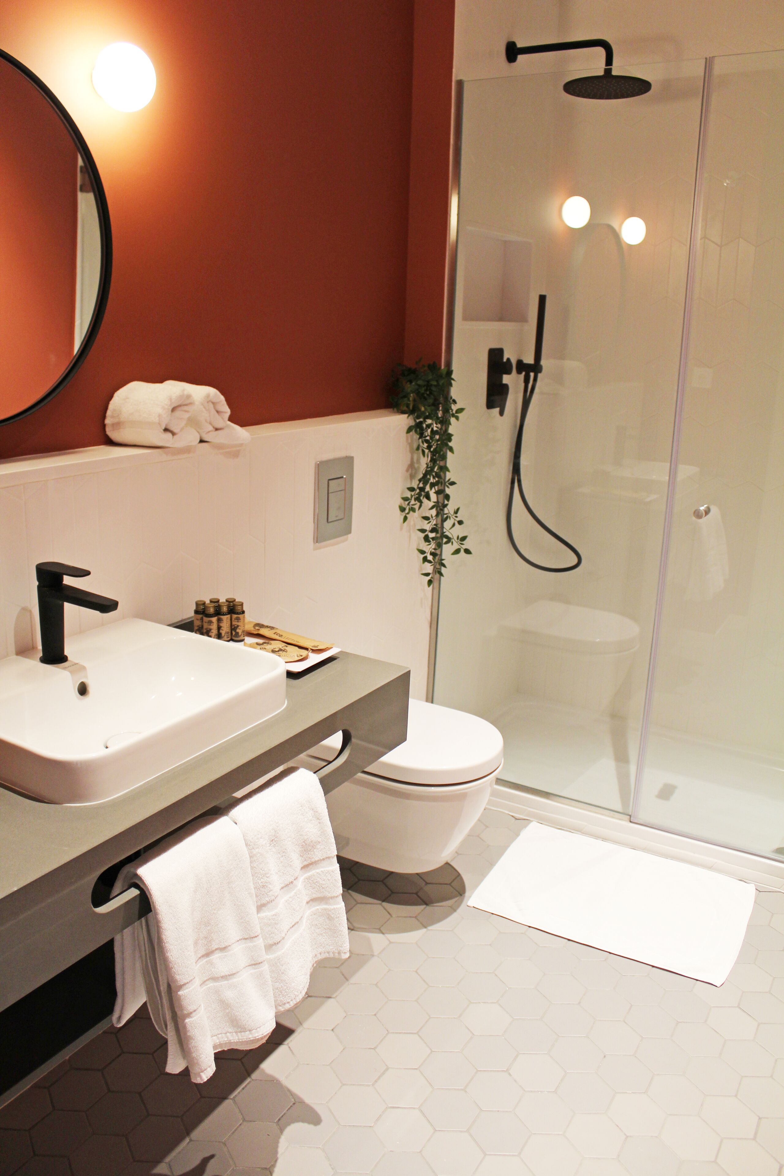 Une salle de bain moderne avec un lavabo blanc, un robinet noir et une douche à l’italienne.