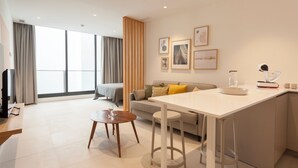 A modern living room with a sofa, a dining area with a table and chairs, and a kitchen area with a counter and stools. - Apartamentos Málaga Premium - Calle Granada (Málaga)
