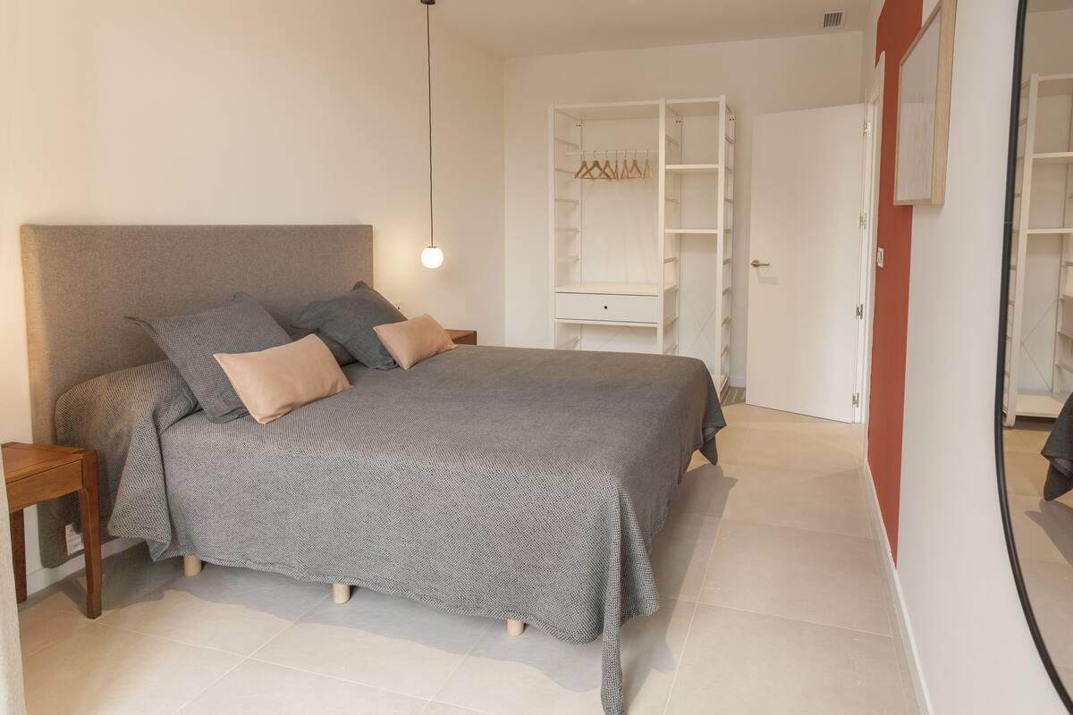Een slaapkamer met een bed, nachtkastjes, een kledingkast en een spiegel.