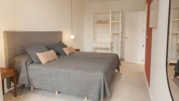 Ein Schlafzimmer mit Bett, Nachttischen, einem Kleiderschrank und einem Spiegel.