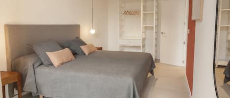 A bedroom with a bed, bedside tables, a wardrobe, and a mirror.