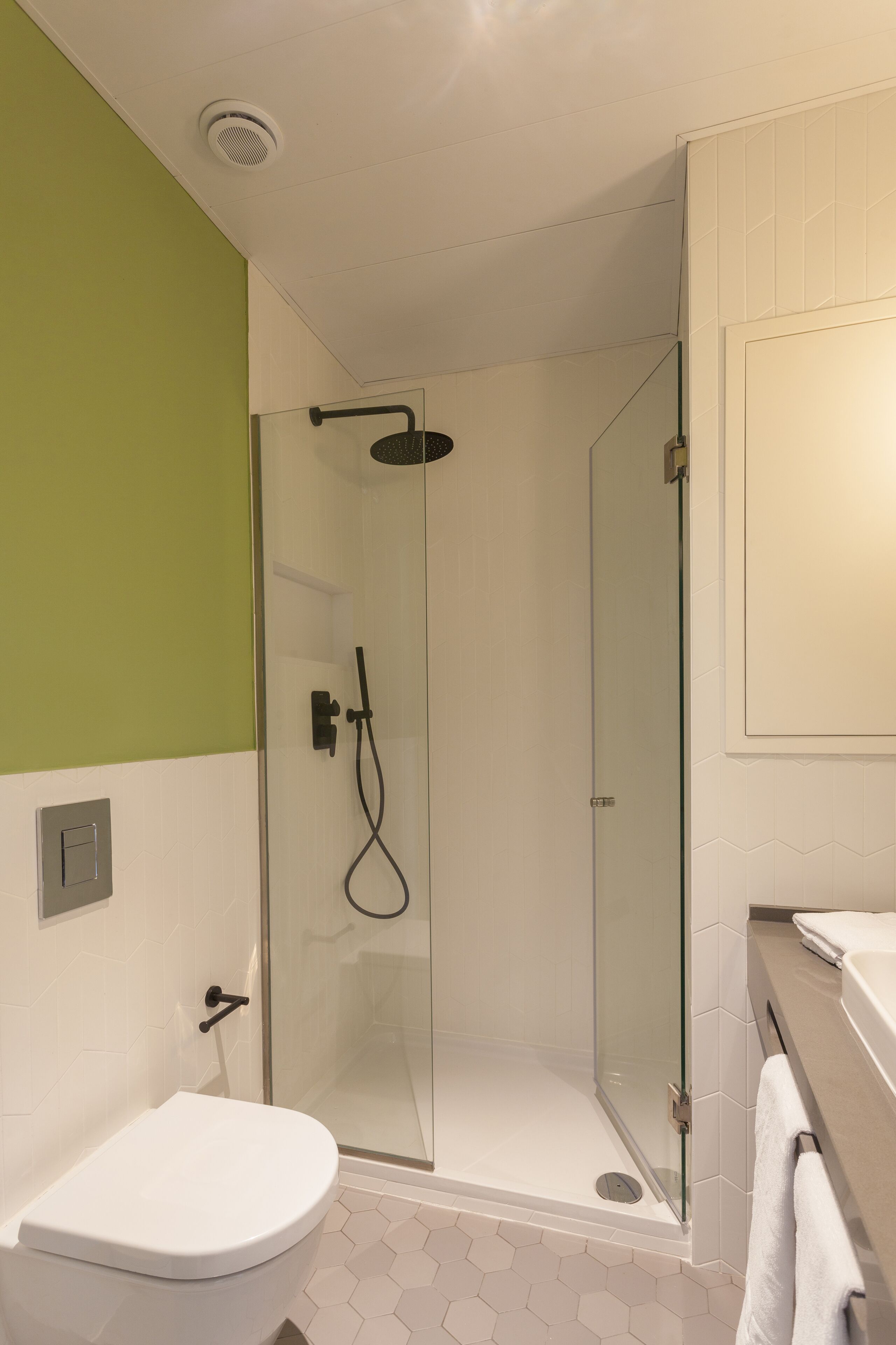 A modern bathroom with a glass-enclosed shower, a white toilet, and a tiled floor.