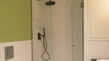 Un baño moderno con ducha de vidrio, inodoro blanco y piso de baldosas.
