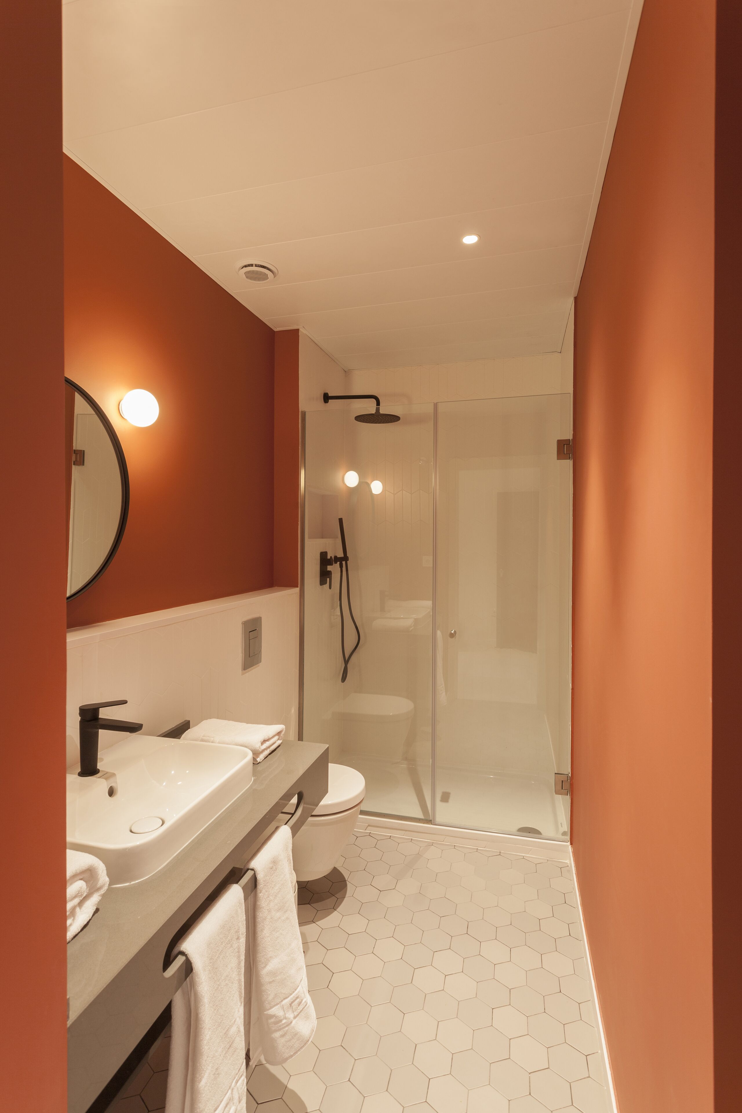 Une salle de bain moderne avec une douche à parois de verre, un meuble-lavabo avec un évier et un miroir, et des toilettes.