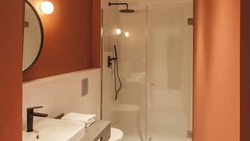 A modern bathroom with a glass-enclosed shower, a vanity with a sink and mirror, and a toilet.