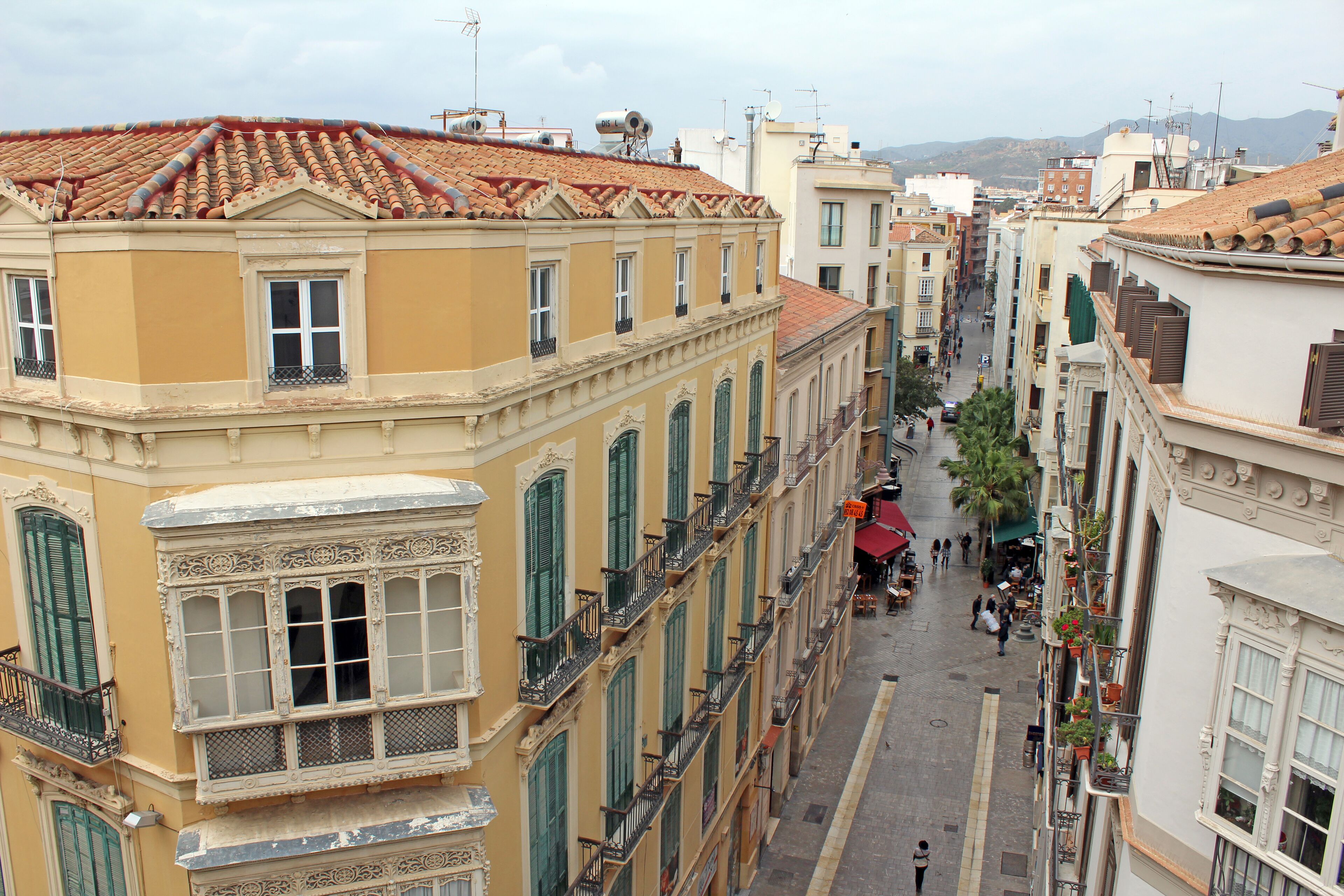 A narrow street lined with historic buildings featuring ornate facades and balconies.