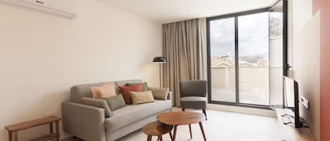 A modern living room with a sofa, two wooden side tables, a chair, and a TV.
