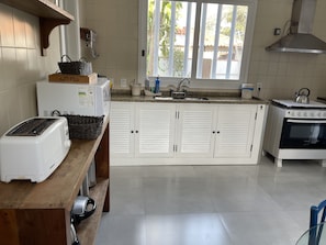 A kitchen with white cabinets, a toaster, a kettle, and a stove.