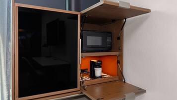 Una kitchenette compacta con microondas, cafetera y un mueble pequeño.