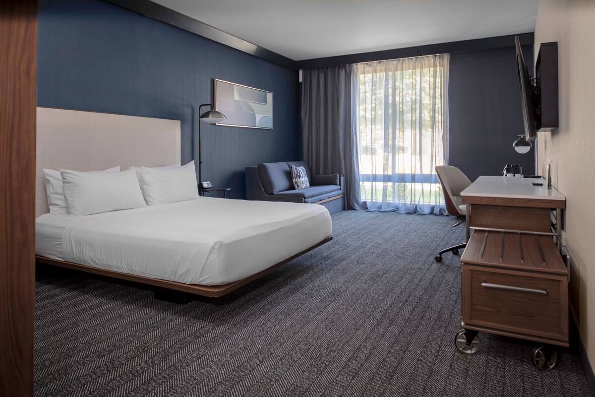 Een hotelkamer met een groot bed, een bureau, een stoel en een televisie.