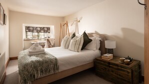 A bedroom with a bed, bedside table, lamp, and a dresser. - Coniston House (Cheltenham)