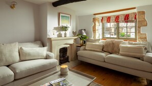 A cozy living room with two sofas, a fireplace, and a window with decorative valance. - Coniston House (Cheltenham)