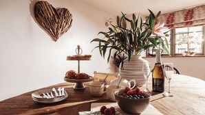 A wooden table with a heart-shaped decoration, a potted plant, a wine bottle, and a bowl of fruit. - Coniston House (Cheltenham)