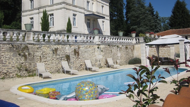 A large stone building with a swimming pool, lounge chairs, and potted plants. - Chateau Du Mas - Classic, Elegant, Beautiful (Dignac)