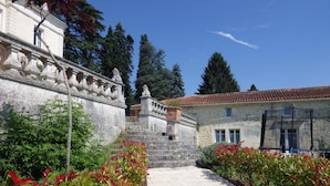 A pathway leading to a stone building with a tiled roof, surrounded by greenery and a stone wall. - Chateau Du Mas - Classic, Elegant, Beautiful (Dignac)