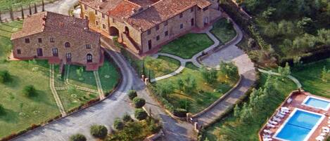 An aerial view of a large estate with multiple buildings, a swimming pool, and well-maintained gardens.