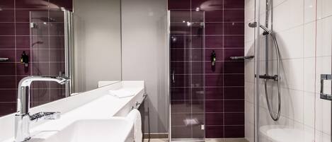 A modern bathroom with a glass-enclosed shower, a white sink, and a large mirror.