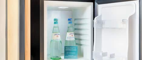 A refrigerator with two bottles of Gerolsteiner Nature water and a complimentary water sign.