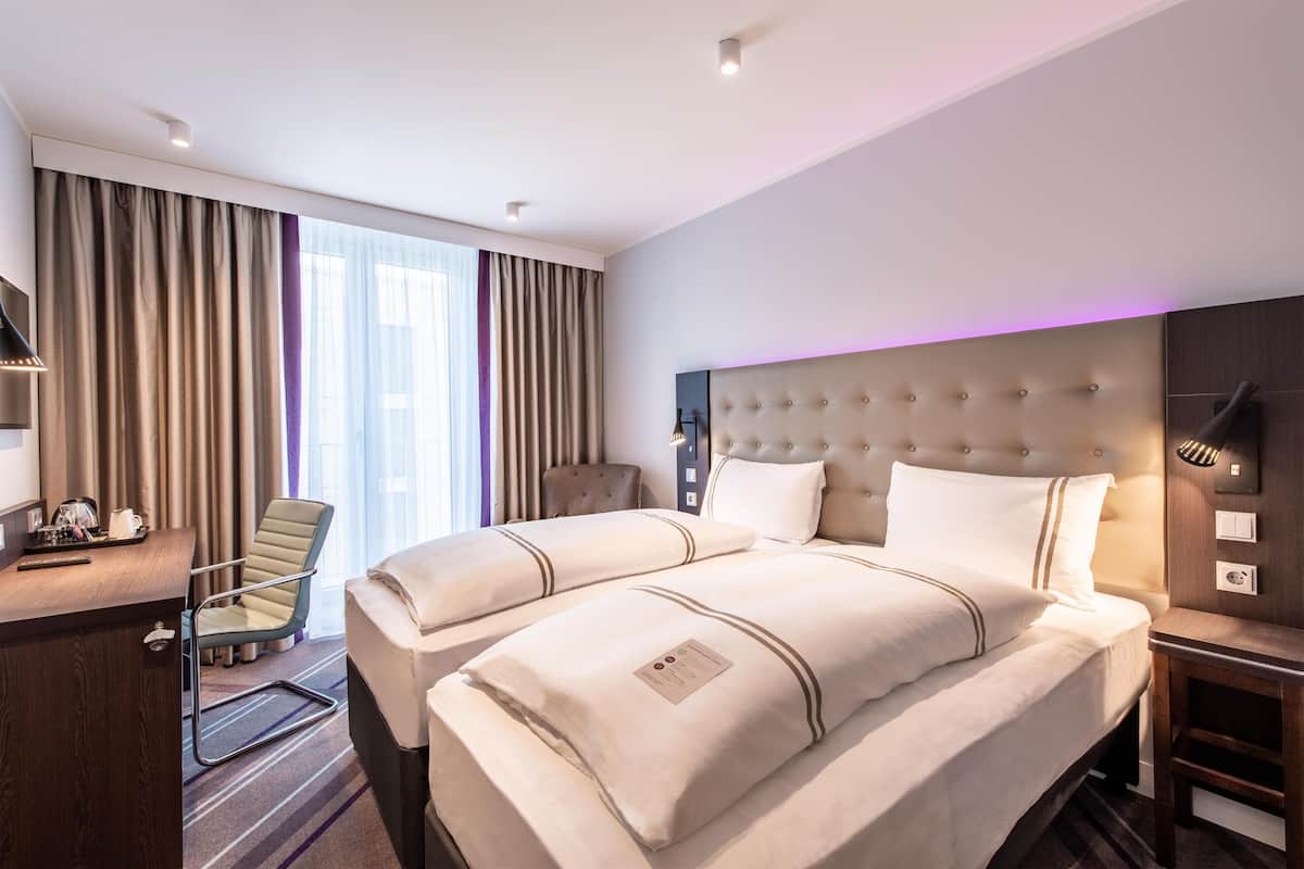 A hotel room with a large bed, a desk, a chair, and a TV.