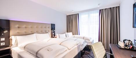 Una habitación de hotel con una cama grande, un escritorio, una silla, un televisor y una ventana con cortinas.