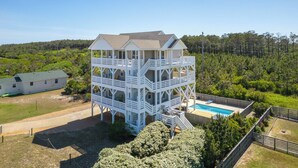 A multi-level wooden structure with a pool, surrounded by greenery. - Mariner's Star Five Bedroom Home in Nags Head with Private Pool and Hot Tub (Nags Head)