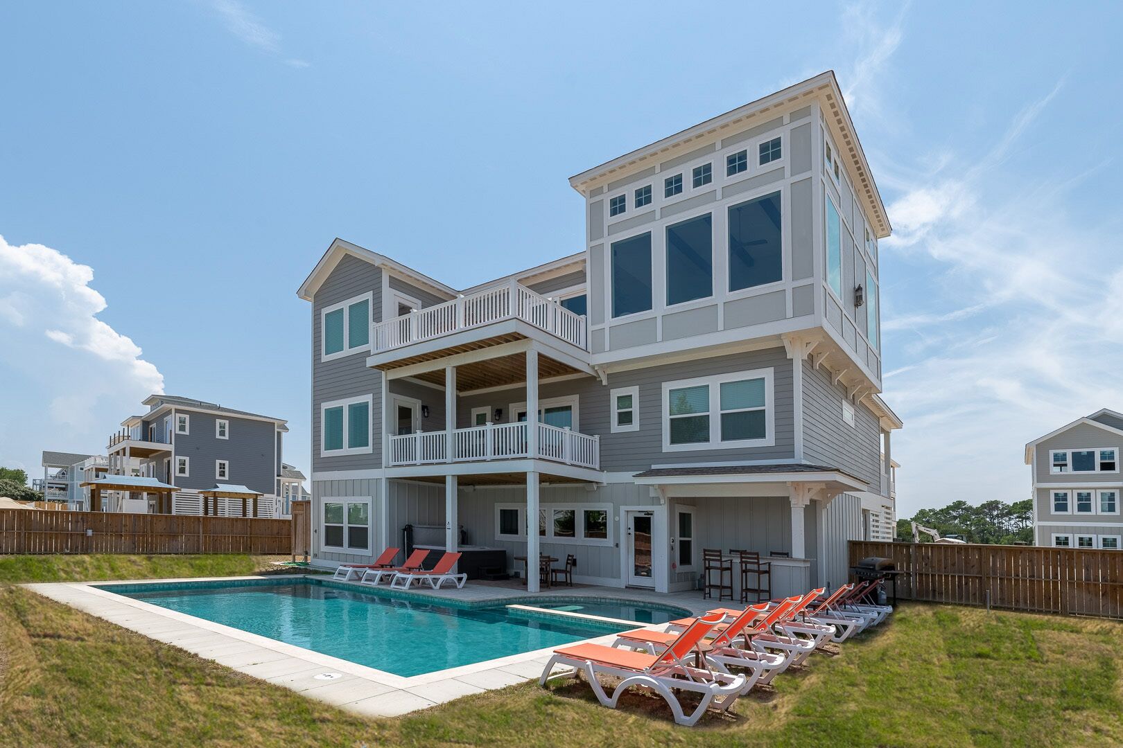 A multi-story house with a swimming pool and outdoor seating.