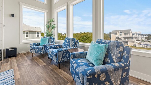 A sunlit room with large windows, a potted plant, and a seating area with patterned sofas. - Coastal Oasis in Corolla + Private Pool + Near the Beach (Corolla)