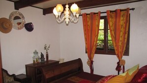 A bedroom with a wooden bed, a nightstand, a dresser, and a chandelier. - F3 apartment in the heart of Petite Ile (Saint-Pierre)