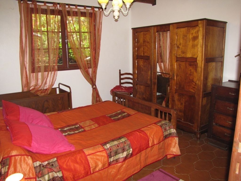 Una habitación con una cama, un armario de madera y una silla.