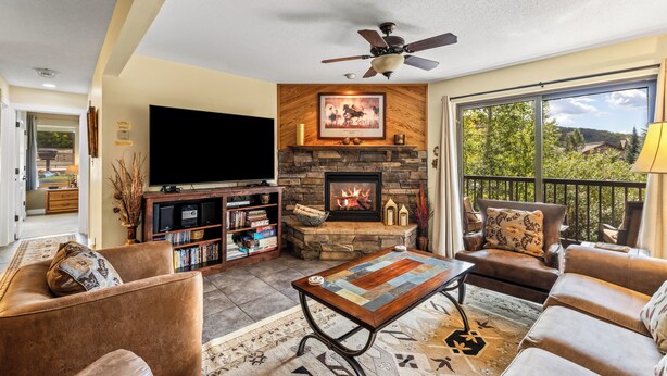 Una sala de estar con chimenea, televisor y balcón con vistas.