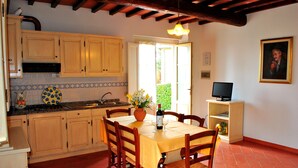 A kitchen with wooden cabinets, a tiled backsplash, a dining table with chairs, and a television on a stand. - Lodging in Tuscany,pool,children pool,Aircon,family and children friendly, sl3 (Montaione)