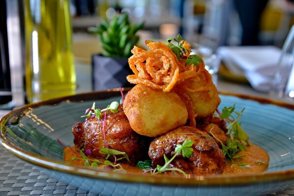 Un plato de comida con albóndigas, alimentos fritos y guarniciones sobre una mesa.