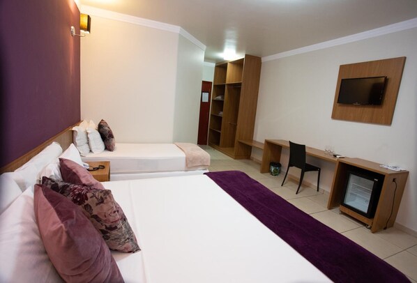 A hotel room with two beds, a desk, a TV, and a wardrobe. - Hotel Havana Express (Uberaba)
