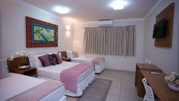 A hotel room with two beds, a desk, a TV, and a painting on the wall.