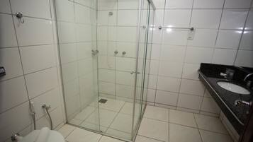 Un baño con ducha envuelta en vidrio, un inodoro y un lavamanos con encimera negra.