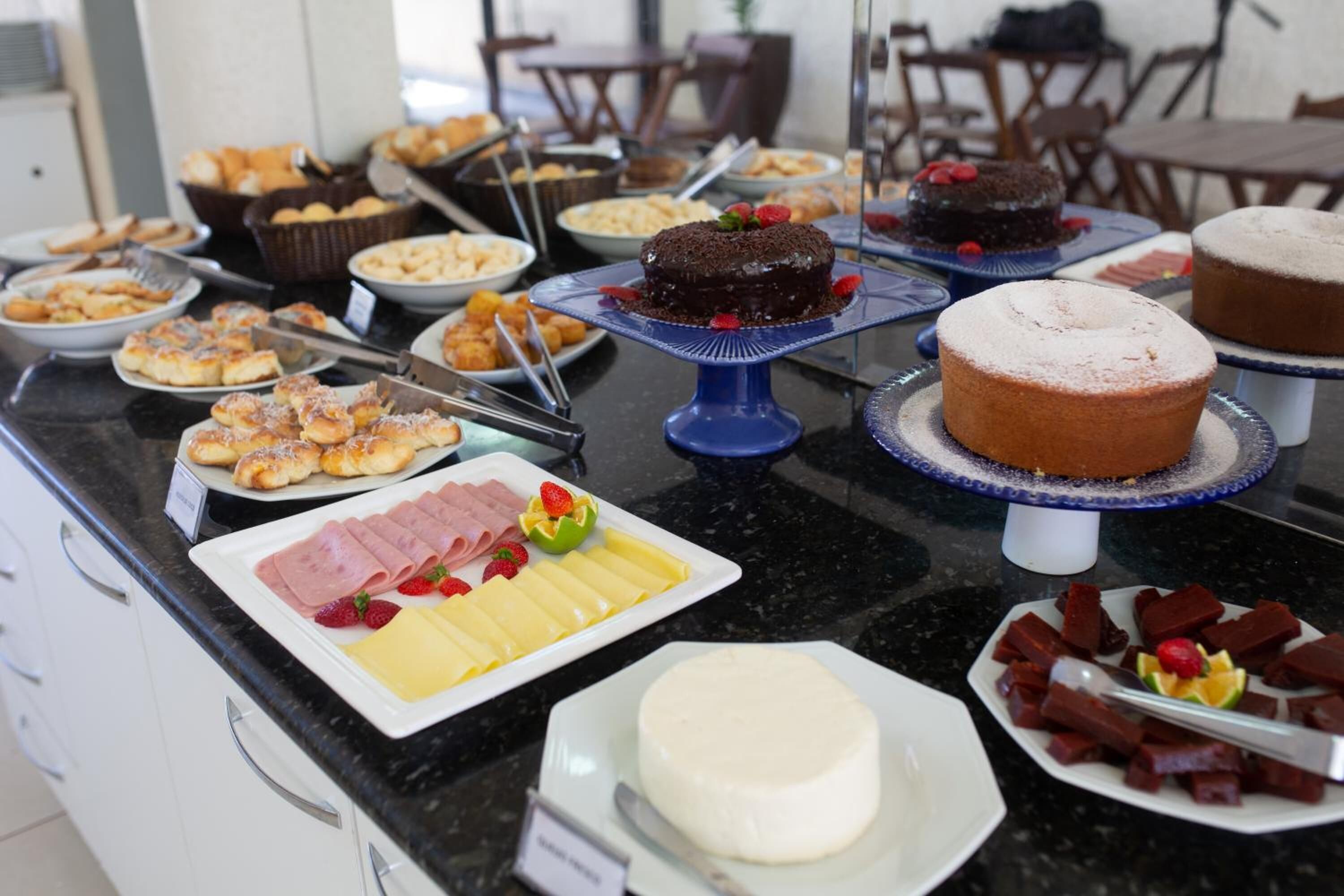 A buffet with various food items including cakes, pastries, and cheese.