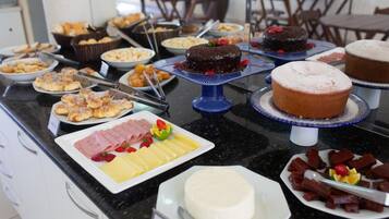 A buffet with various food items including cakes, pastries, and cheese.