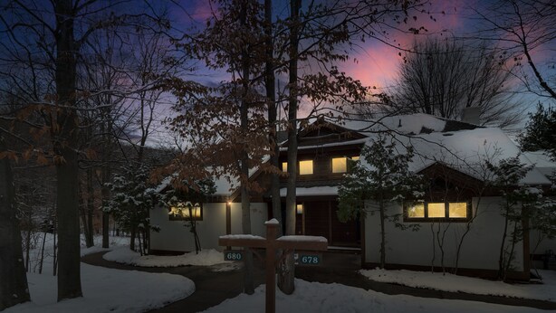 Uma casa de dois andares com telhado coberto de neve e um caminho que leva à entrada.
