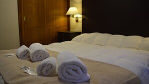 A hotel room with a bed, a wooden door, a nightstand, and a lamp. - Hotel Nordico (San Carlos de Bariloche)
